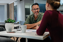 A man and woman collaborating at a table in an office environment, focused on their discussion.