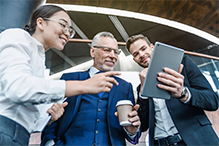 Three business professionals looking at a tablet.