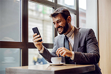 A business man smiling at his phone.