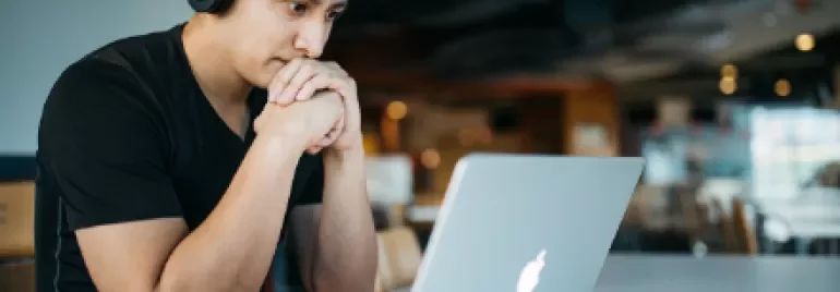 Person wearing headphones, focused on a laptop in a modern cafe.